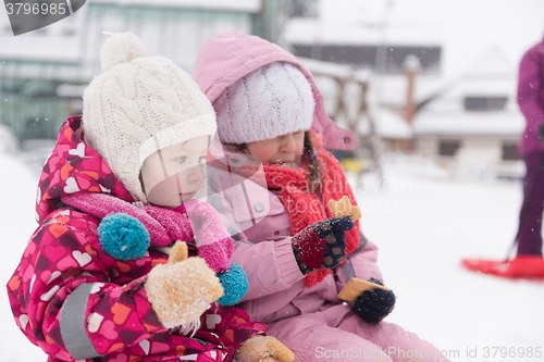 Image of portrait of two little grils sitting together on sledges