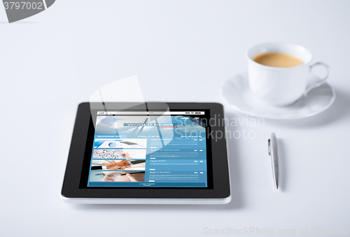 Image of tablet pc with world news web page and coffee