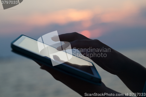 Image of Woman hands typing on pad outdoor at sunset