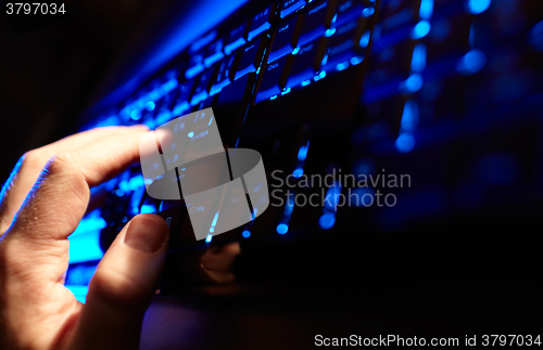 Image of Man\'s hand typing on a blue keyboard.