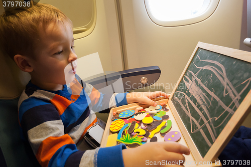 Image of Boy in the plane drawing on board with chalk