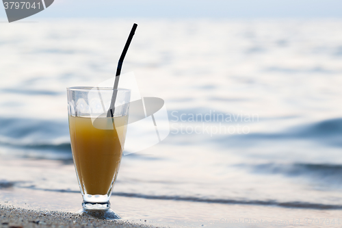 Image of Glass of cocktail on beach near water