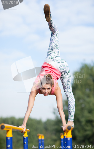 Image of Agile young gymnast balancing on cross bars