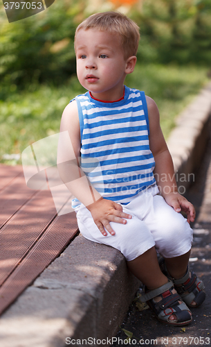 Image of Cute boy sitting on the curb