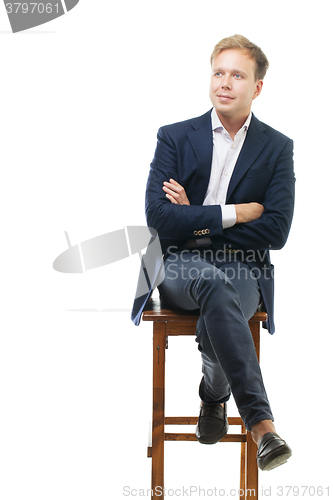 Image of Young businessman sitting on high wooden chair