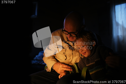 Image of Grandfather hugs his grandson near fireplace