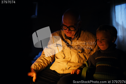 Image of Grandfather and grandson near fire at home.