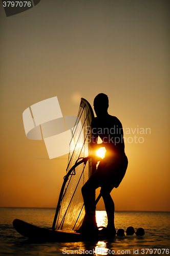 Image of Man sailboarding at sunset