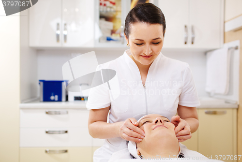 Image of Professional beautician during the seance of facial massage