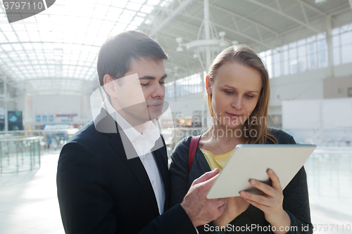 Image of Young businesspeople with pad in shopping centre