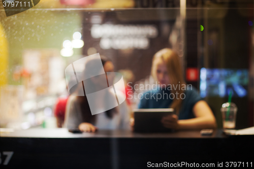 Image of Two female friends using tablet PC in a cafe