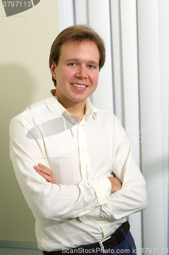 Image of Happy young man with folded arms indoor