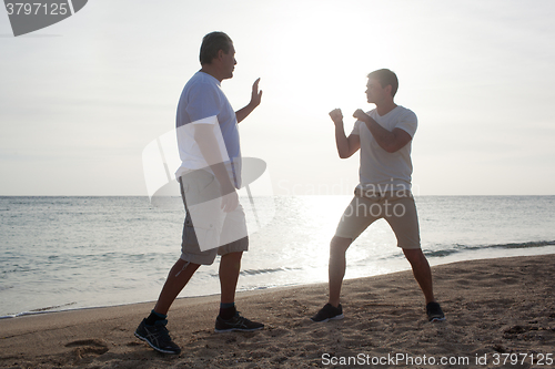 Image of Two men having boxing training on the beach