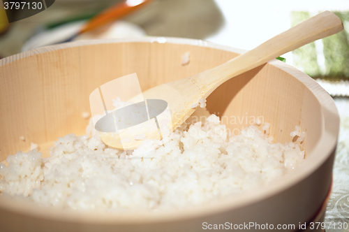 Image of Cooking sushi. Mixing rice in a wooden plate.