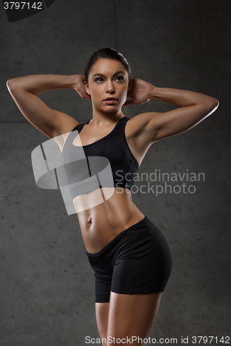 Image of young woman posing and showing muscles in gym