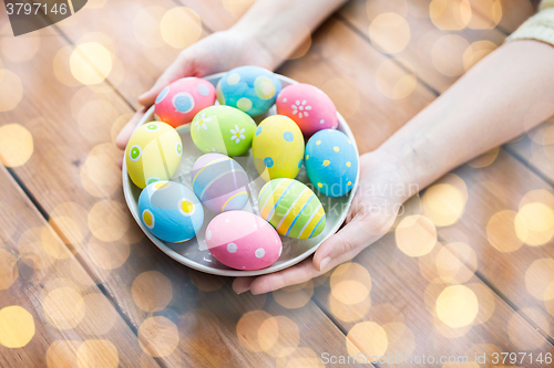 Image of close up of woman hands with colored easter eggs