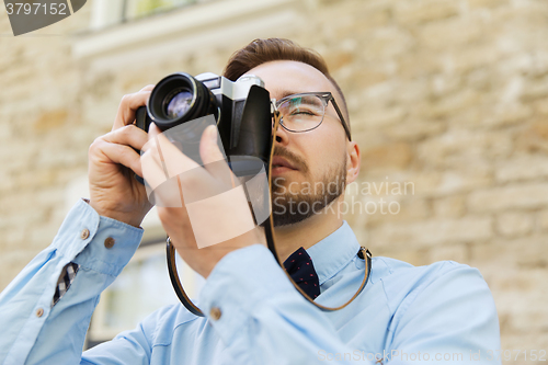 Image of young hipster man with film camera in city