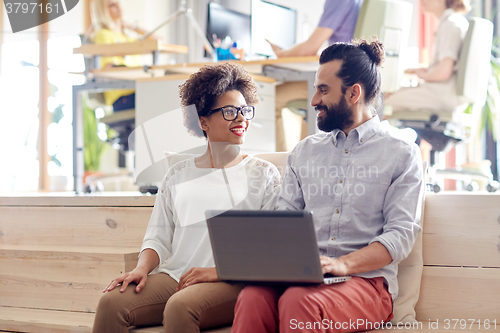 Image of happy creative team with laptop in office