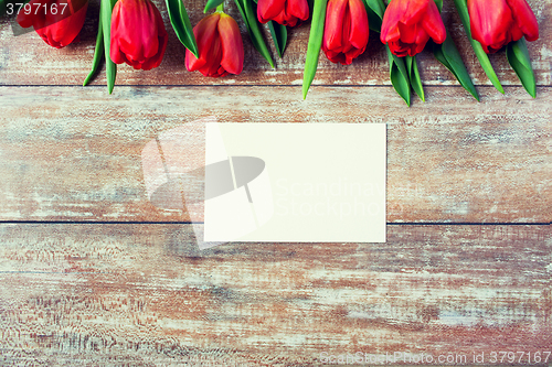 Image of close up of red tulips and blank paper or letter