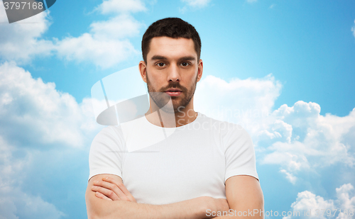 Image of young man with crossed arms over blue sky