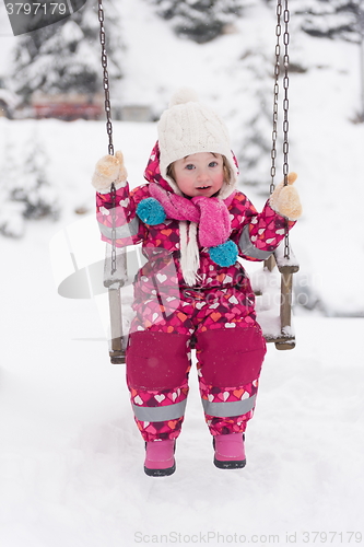 Image of little girl at snowy winter day swing in park