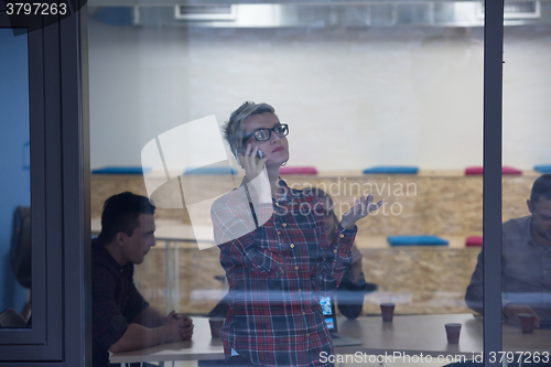 Image of business woman in meeting room  speaking by cell phone