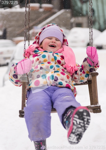 Image of little girl at snowy winter day swing in park