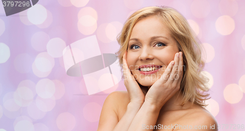 Image of smiling woman with bare shoulders touching face