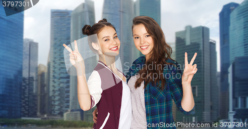 Image of happy teenage girls hugging and showing peace sign