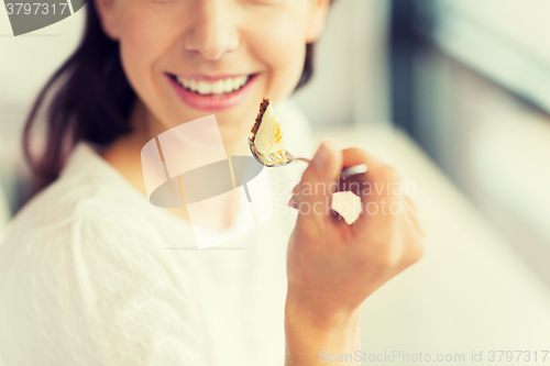 Image of close up of woman eating cake at cafe or home