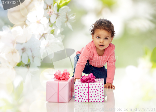 Image of baby girl with birthday presents and confetti