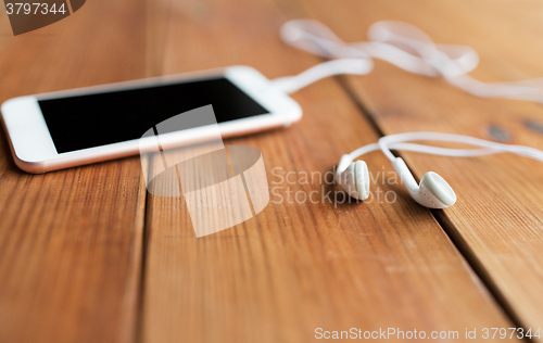 Image of close up of blank smartphone and earphones on wood