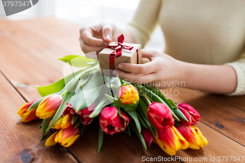 Image of close up of woman with gift box and tulip flowers