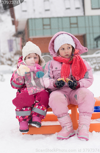 Image of portrait of two little grils sitting together on sledges