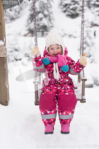 Image of little girl at snowy winter day swing in park