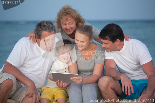 Image of Happy big family with tablet PC on the beach