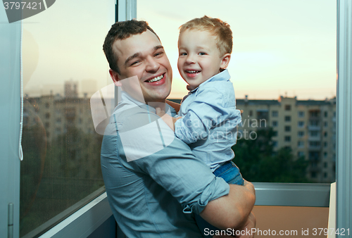 Image of Young father and son smiling on the balcony.