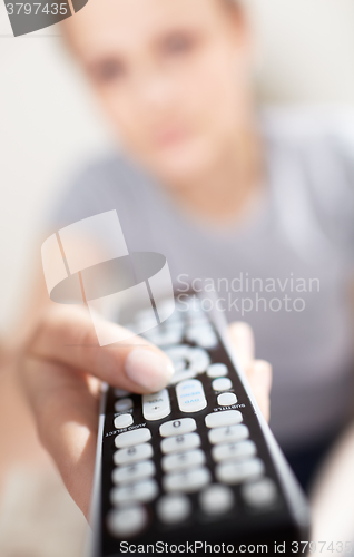 Image of Young woman with remote watching TV.