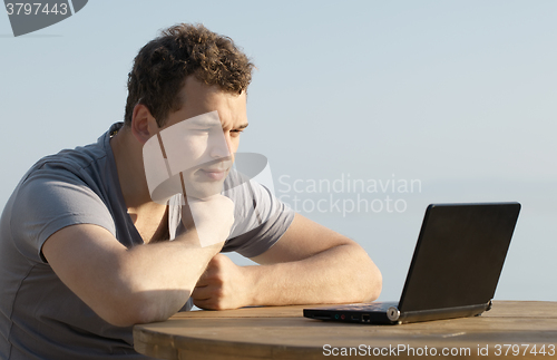 Image of Man looking to the display of small laptop computer