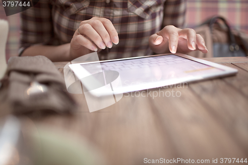 Image of Woman in cafe typing on touch pad