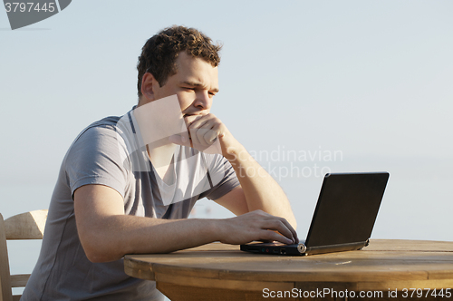 Image of Man typing on a small laptop computer