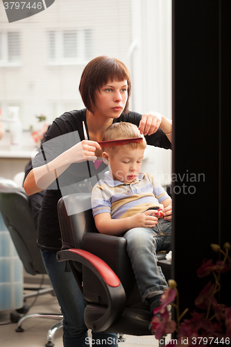 Image of Little boy getting a haircut from hairdresser