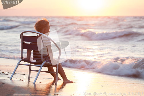 Image of Boy sitting on the chair by sea