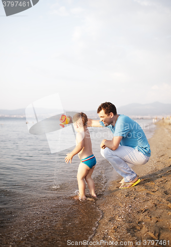 Image of Young father playing with his son at the beach