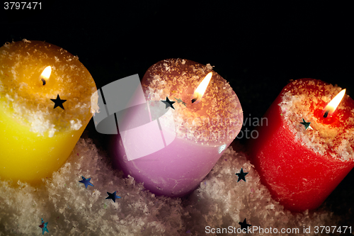 Image of Three candles with artificial snow.