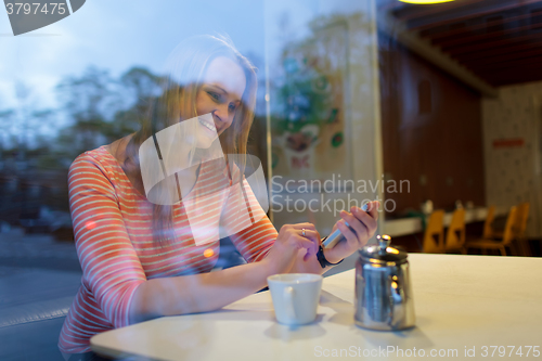 Image of Young woman using a mobile phone in cafeteria