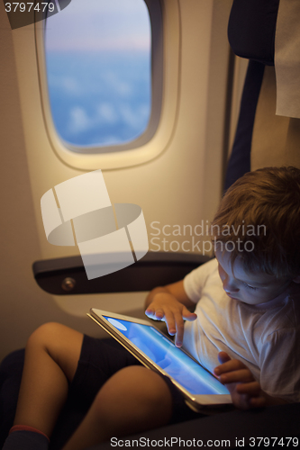 Image of Boy spending time with tablet PC during flight