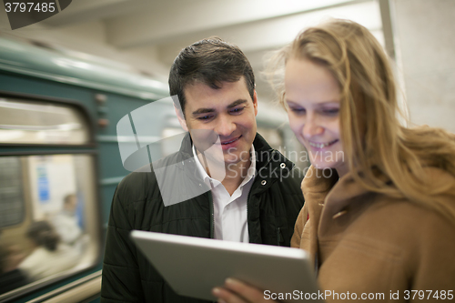 Image of Happy young people with touch pad in subway