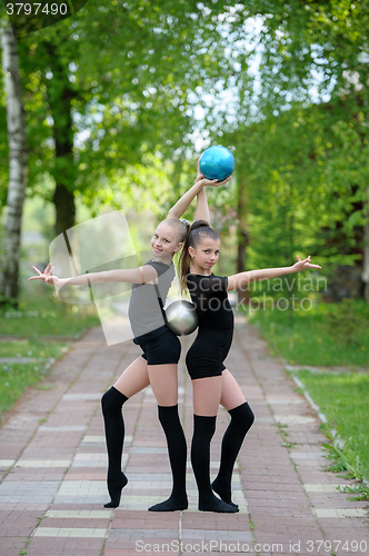 Image of Gymnast girls posing with balls outdoor