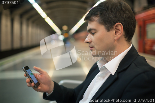 Image of Young man reading sms on smartphone in underground